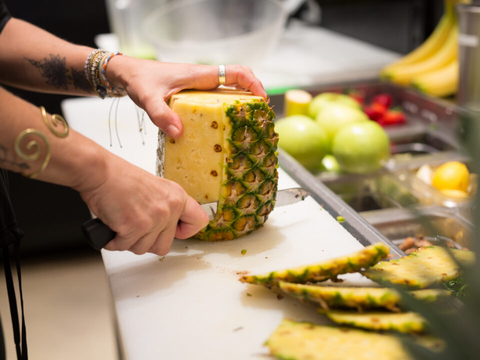 woman cutting a pineapple in a kitchen